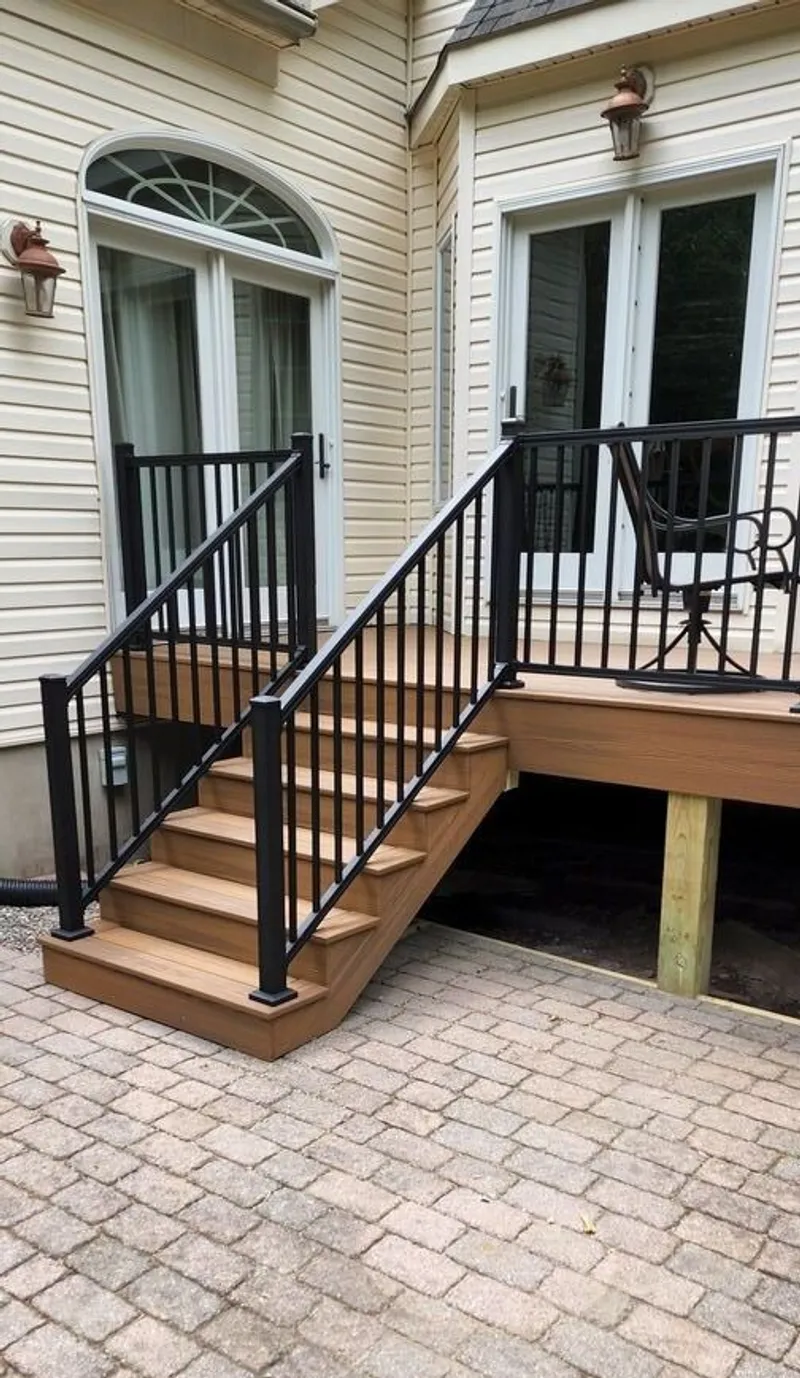 Completed deck and stairs with freshly paintly railing descending into a brick courtyard